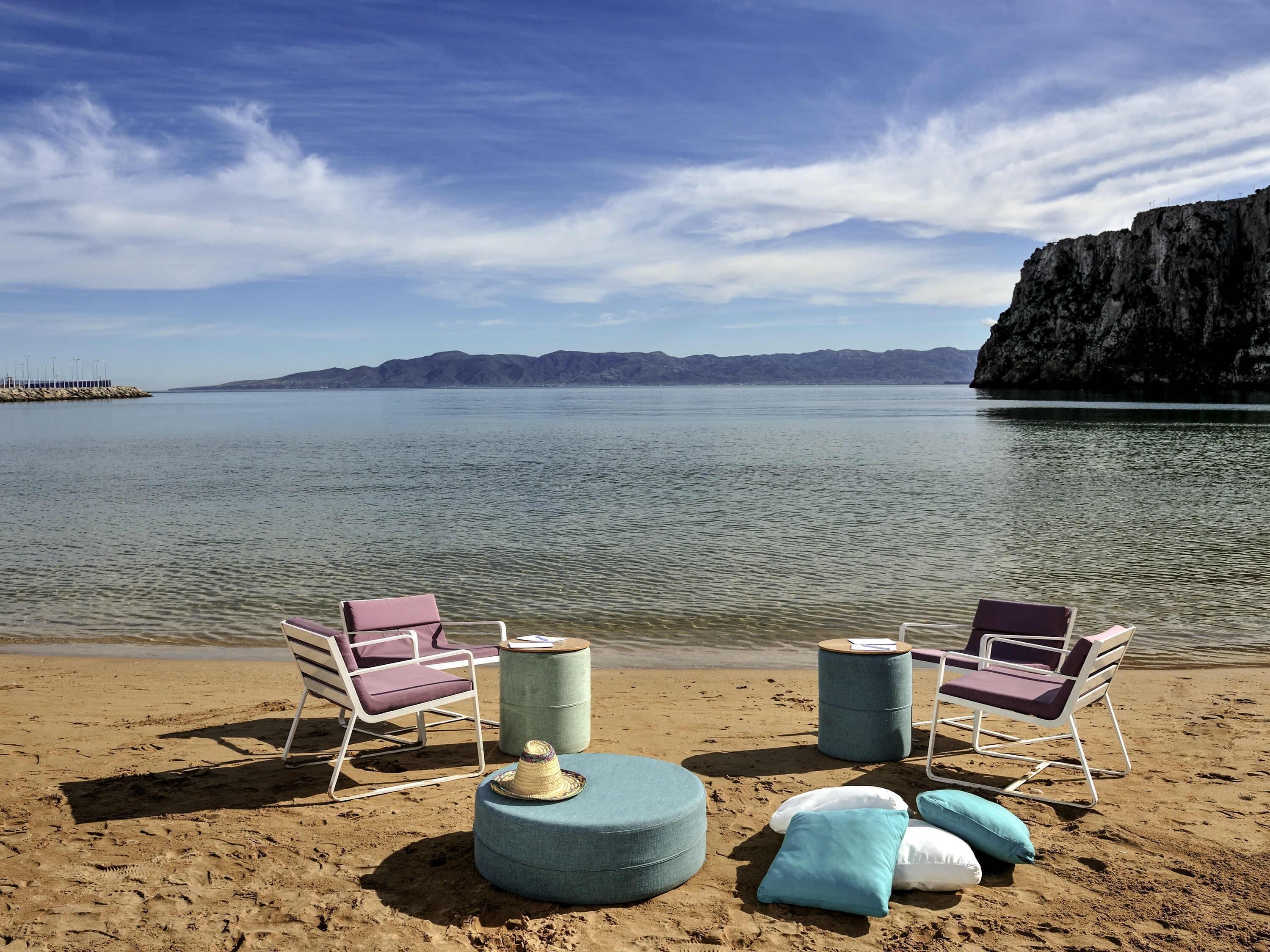 Una playa con dos sillas de playa, reposapiés y cojines.
