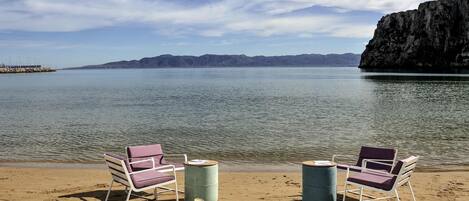Una playa con dos sillas de playa, reposapiés y cojines.