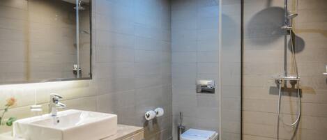 A modern bathroom with a glass shower enclosure, a white sink, and a toilet.
