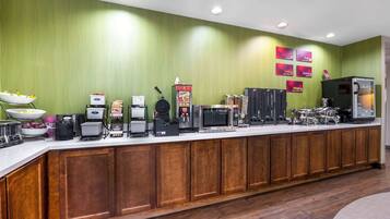 Un comptoir de buffet proposant différents postes de service pour les aliments et les boissons, notamment une machine à café, un four à micro-ondes et un réfrigérateur.