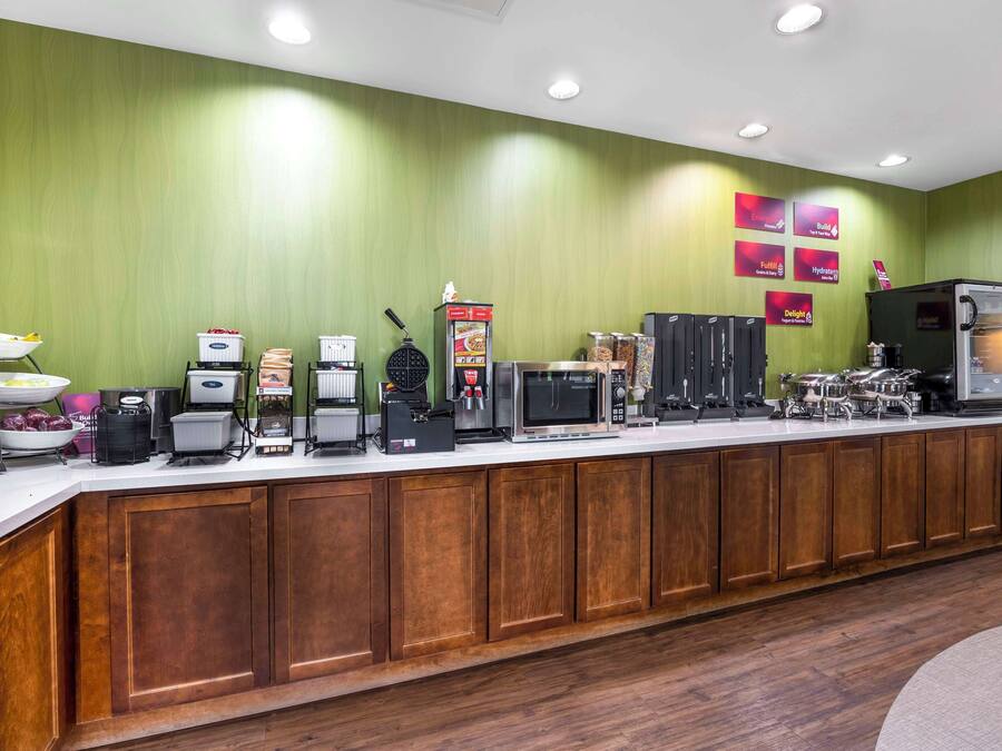 Un comptoir de buffet proposant différents postes de service pour les aliments et les boissons, notamment une machine à café, un four à micro-ondes et un réfrigérateur.