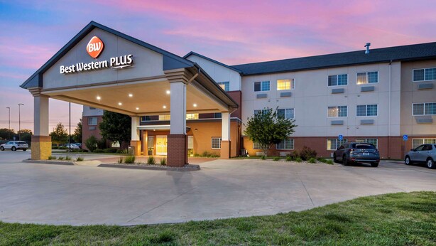 A Best Western PLUS hotel with a covered entrance, multiple parking spaces, and a clear sky. - Best Western Plus Patterson Park Inn (Arkansas City)