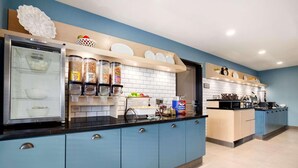 A modern kitchen with blue cabinets, a refrigerator, and various kitchen appliances. - Country Inn & Suites by Radisson Roseville - St. Paul (Roseville)