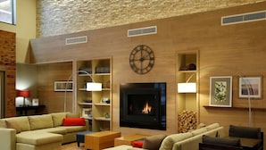 A modern living room with a fireplace, sofas, and a clock on the wall. - Country Inn & Suites by Radisson Roseville - St. Paul (Roseville)
