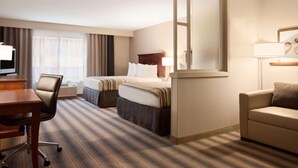 A hotel room with a bed, a desk, a chair, a sofa, a TV, and a window with curtains. - Country Inn & Suites by Radisson Roseville - St. Paul (Roseville)