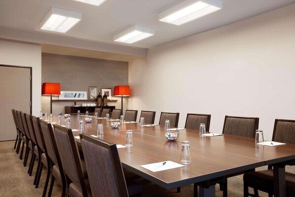 A conference room with a long table, chairs, and two lamps.