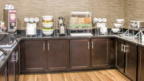 Cozinha moderna com espaço para café, tigelas de frutas e máquina de café.