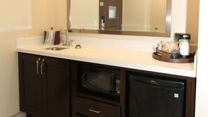Une salle de bain avec un grand miroir, un lavabo, un meuble sombre et un lave-vaisselle encastré.