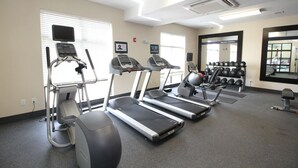 Une salle de sport équipée de tapis de course, d’un appareil elliptique et d’un ensemble d’haltères.