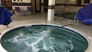 A hot tub with a tiled edge, a pool ladder, and a tiled floor.