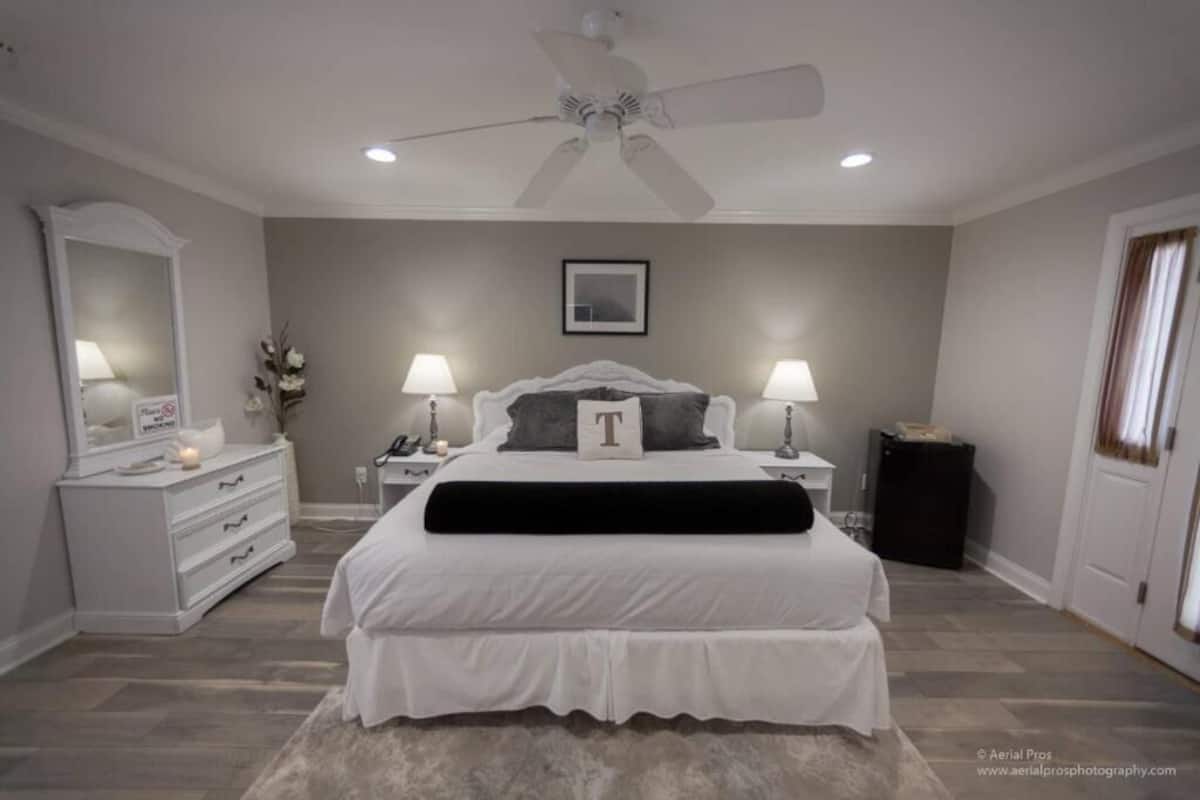 A bedroom with a bed, bedside tables, a dresser, a ceiling fan, and a framed picture on the wall.