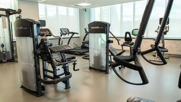 Una palestra con diverse macchine per esercizi, tra cui tapis roulant ed ellittiche, disposte in un ambiente ampio.
