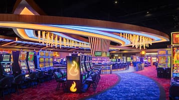 Een casino met meerdere gokkasten, een gebogen plafond met hangende lampen en een vloerbedekking.