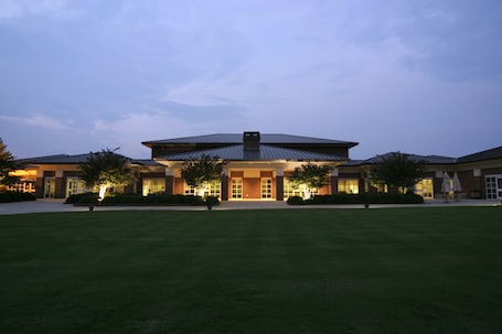 A modern building with a central entrance, surrounded by a well-maintained lawn and trees.