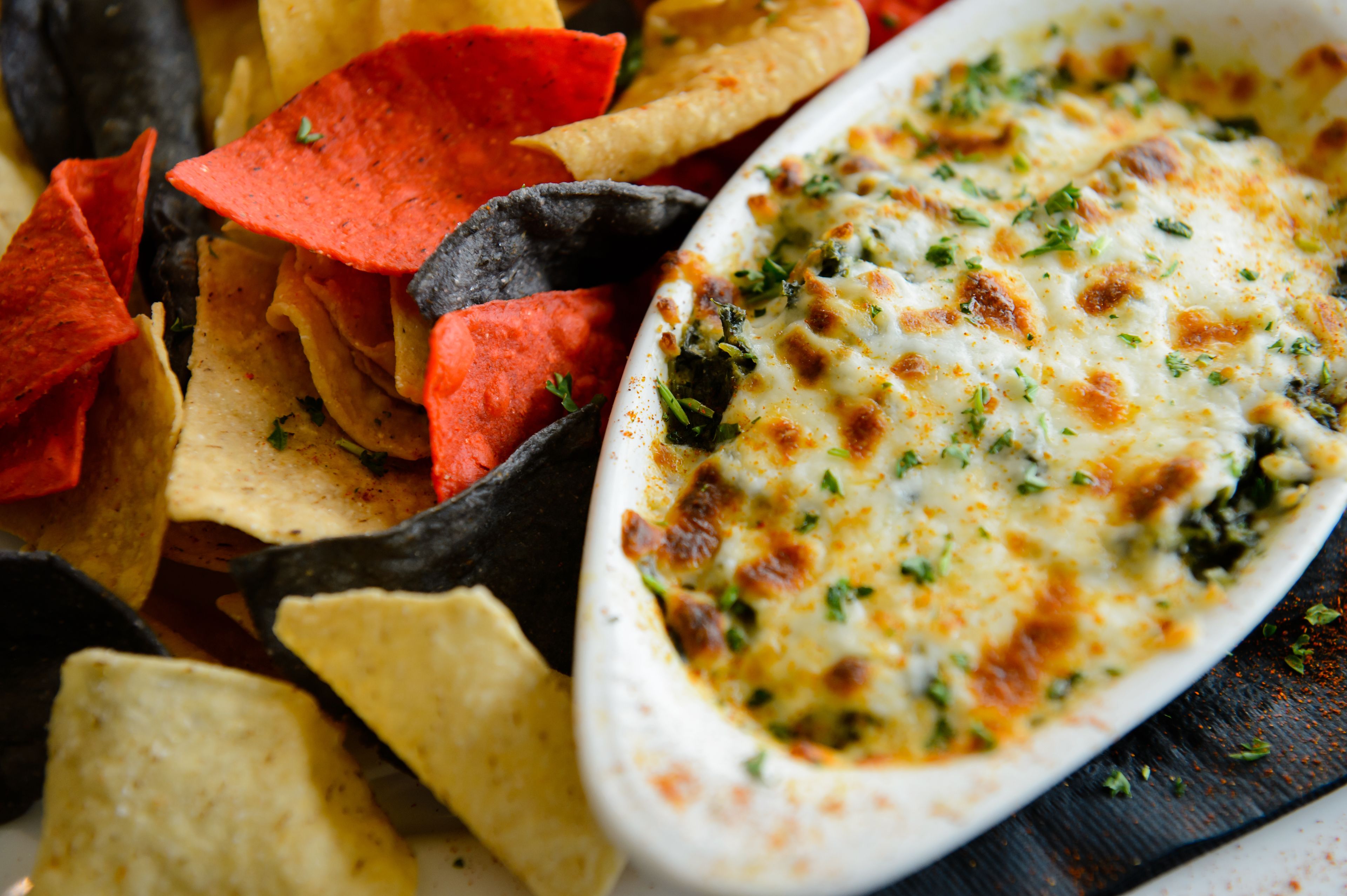 A dish of baked cheese with herbs, surrounded by tortilla chips.