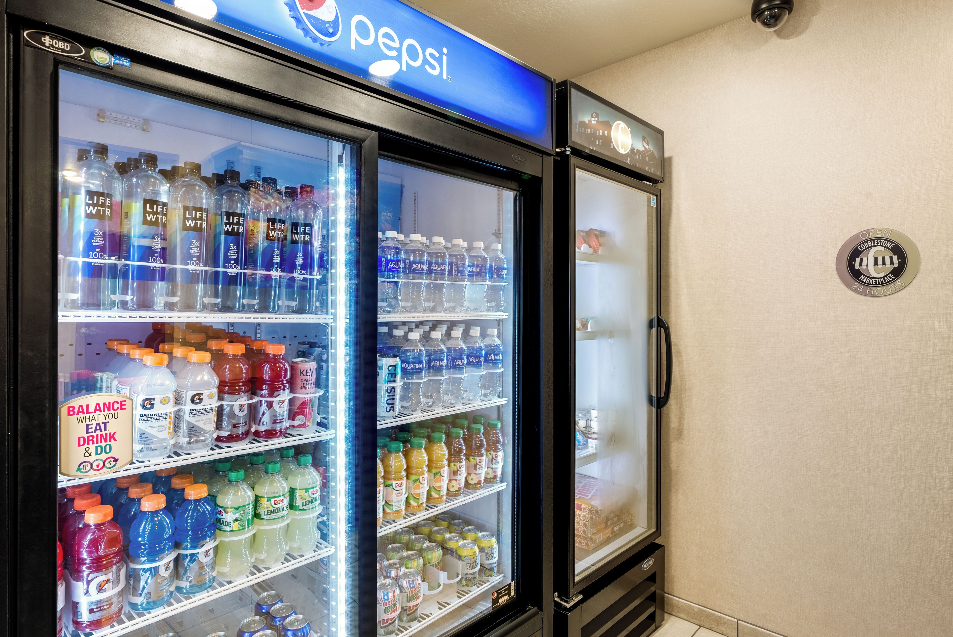Een automaat met een Pepsi-bord, gevuld met diverse drankjes zoals water, sportdranken en frisdranken.