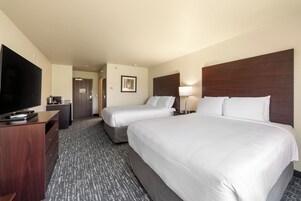 Quarto de hotel com duas camas, televisão, escrivaninha e porta.