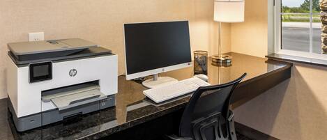 A hotel office with a desktop computer, HP printer, and a lamp.