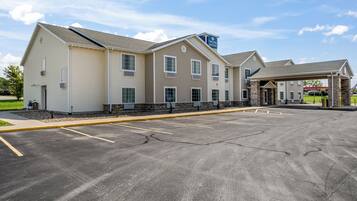A hotel with a parking lot, a covered entrance, and a sign for Cobblestone Inn & Suites.