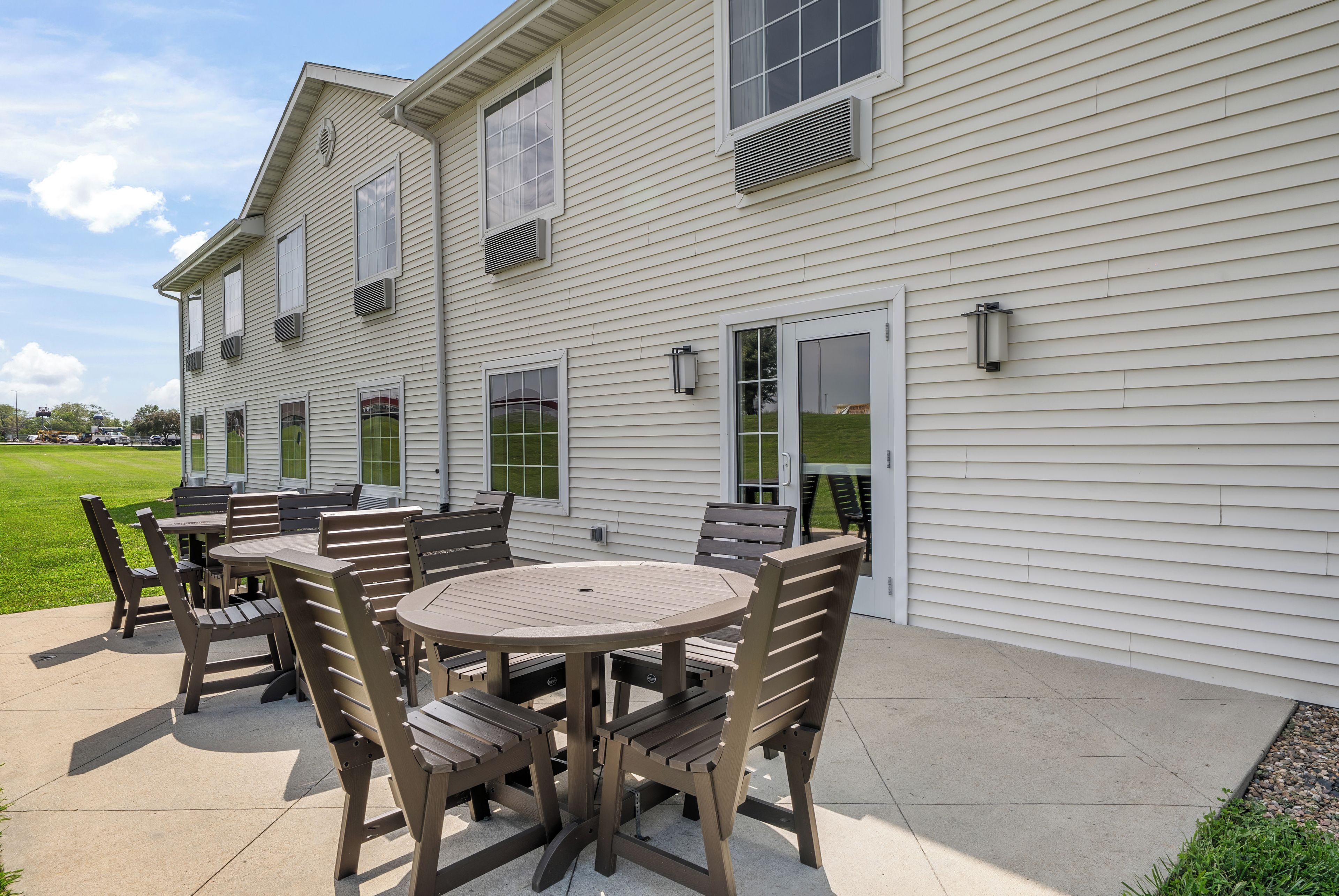 A patio with outdoor furniture and a view of a white building with multiple windows and an air conditioning unit.