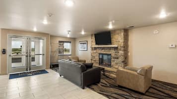 A lobby with a stone fireplace, leather sofas, a flat-screen TV, and a door leading outside.