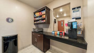 Un hall de hotel con una barra de aperitivos, un cubo de basura y una recepción.