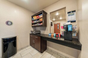 Un hall de hotel con una barra de aperitivos, un cubo de basura y una recepción.