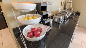 Un bufé de desayuno con frutas y un tostador.
