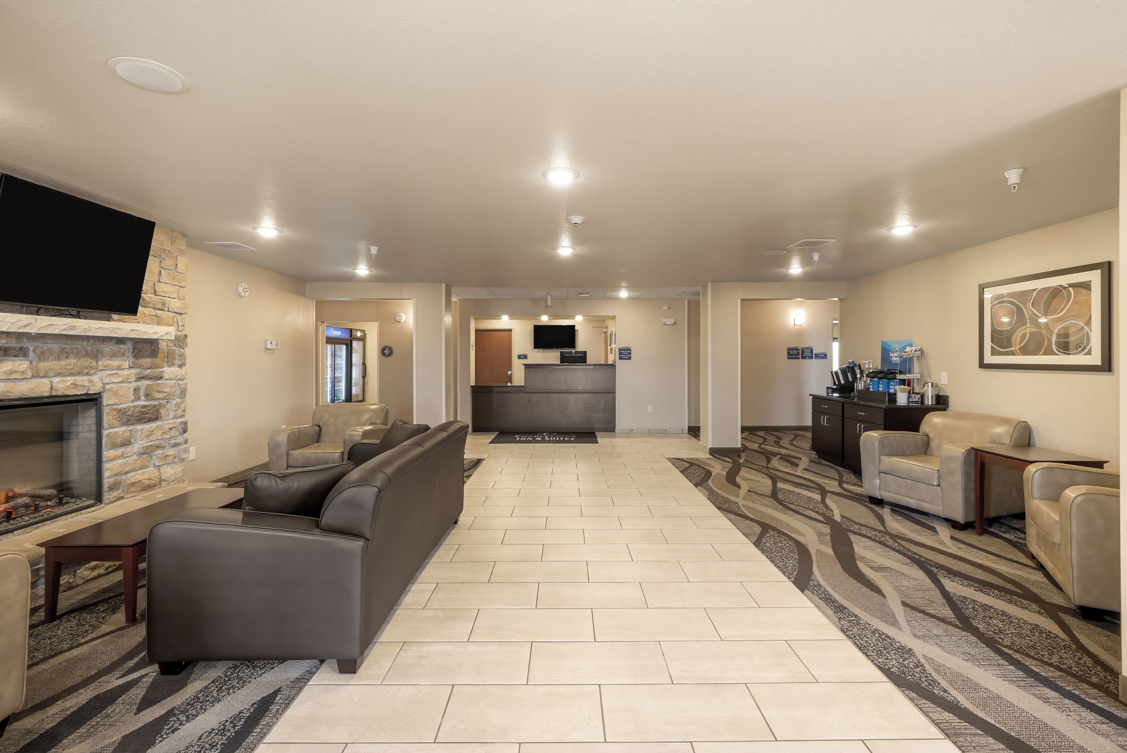 A spacious living area with a fireplace, leather sofas, a flat-screen TV, and a kitchen in the background.