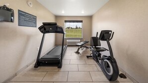 Un gimnasio con cinta de correr, bicicleta estática y banco.
