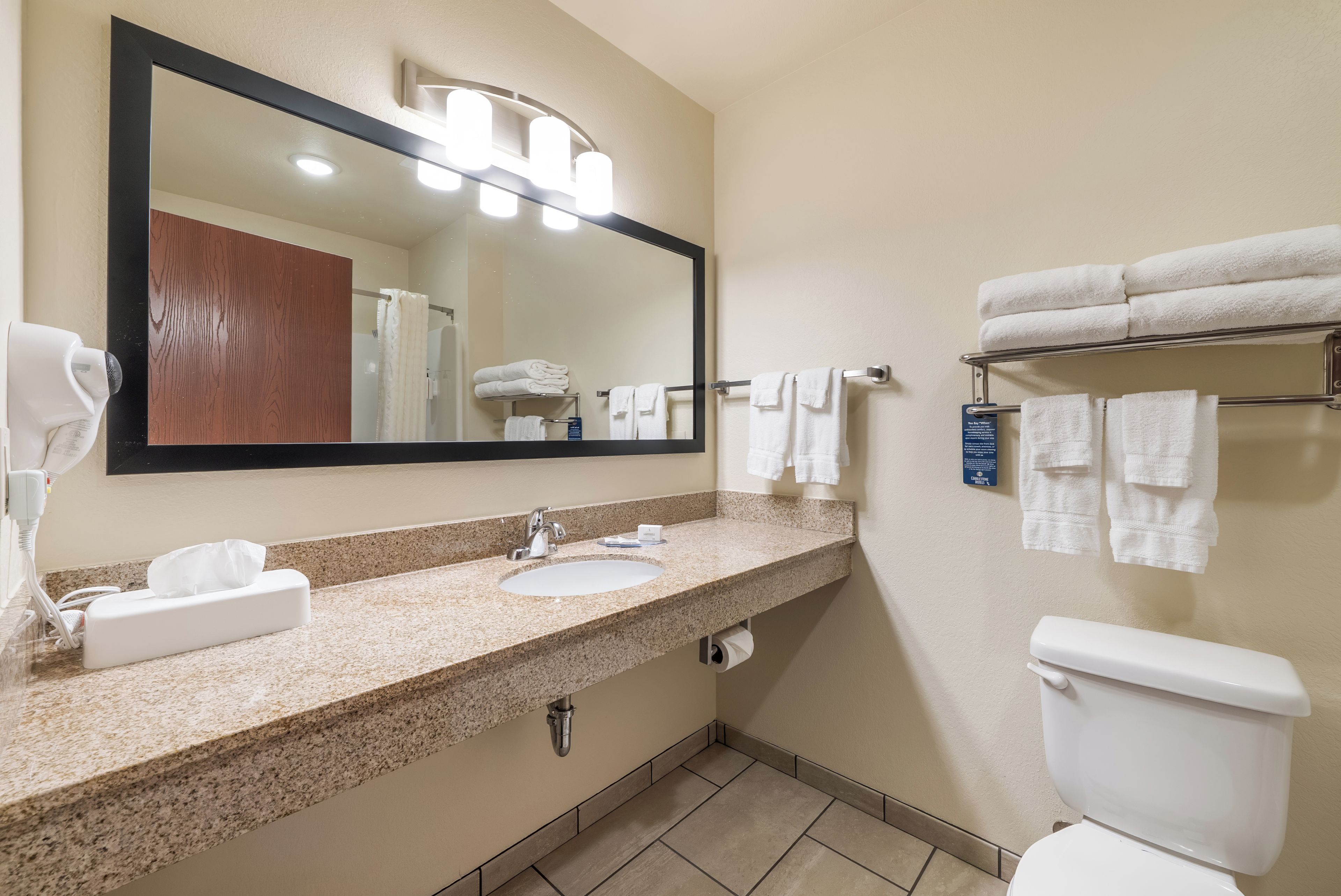 A bathroom with a granite countertop, a sink, a mirror, a towel rack, and a toilet.