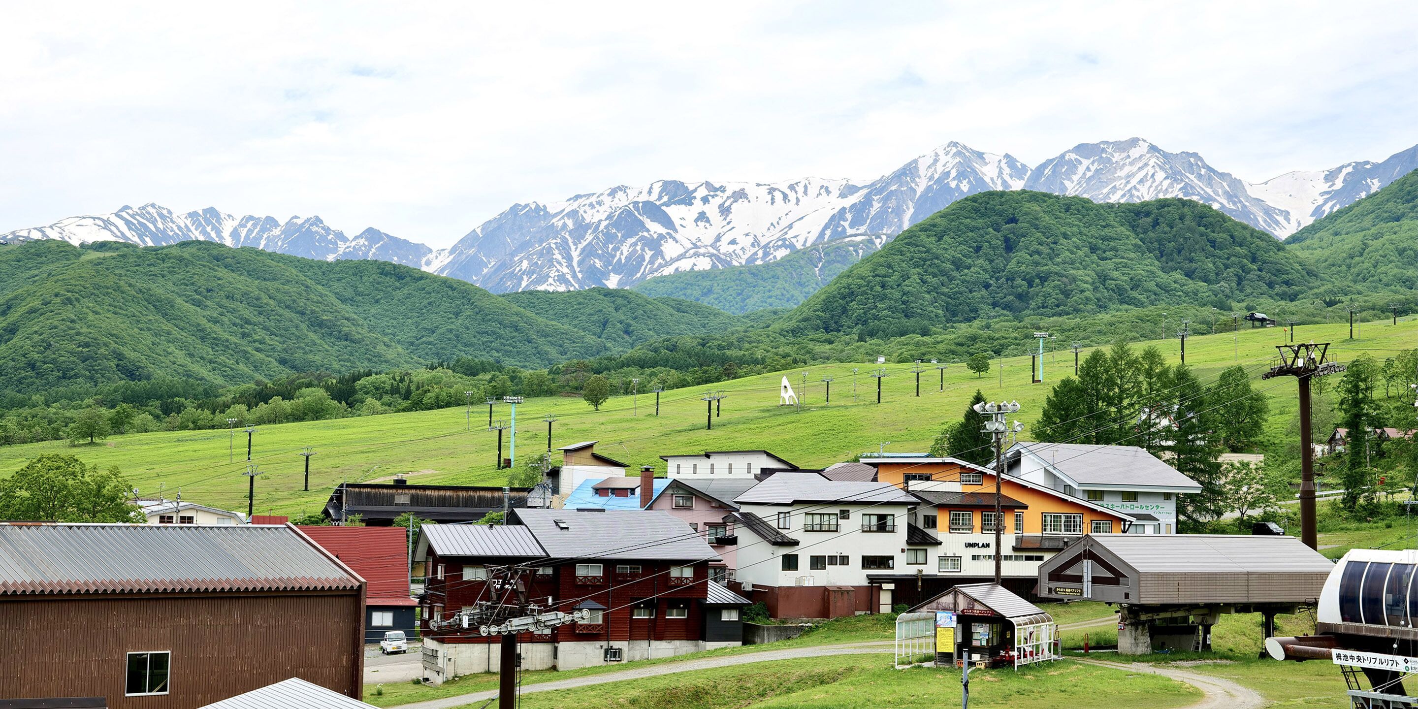 Un pittoresco villaggio rurale con case, un piccolo edificio e montagne sullo sfondo.