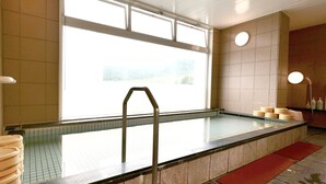 A swimming pool with a metal ladder, tiled walls, and a window providing natural light.