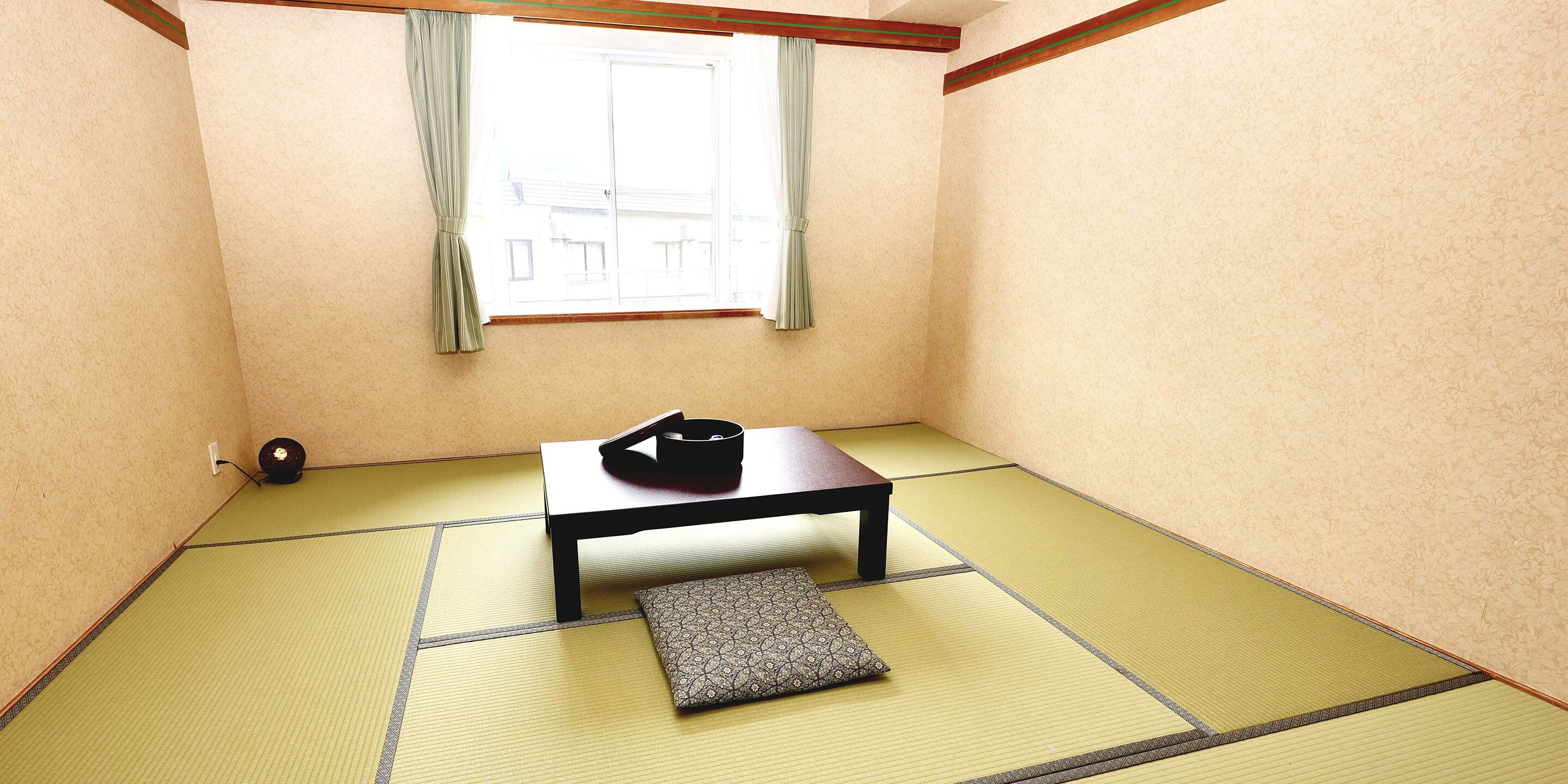 A tatami mat room with a sliding door, a small table, and a cushion.
