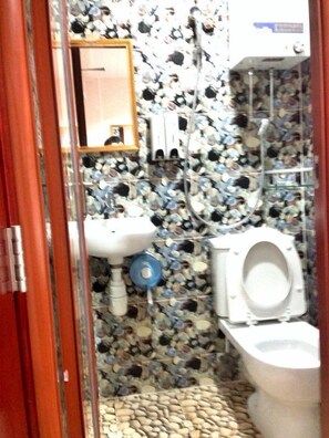 A bathroom with a mosaic tile wall, a sink, a toilet, and a mirror. - New London Hostel (Kowloon)