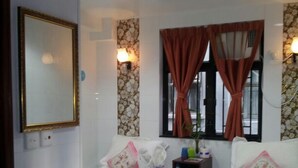 A hotel room with two single beds, a bedside table with a phone, a small nightstand, and a window with curtains. - New London Hostel (Kowloon)