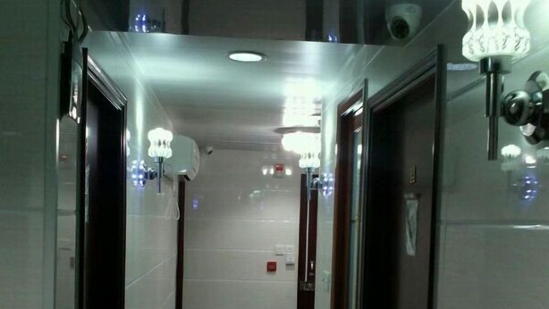 A hallway with a tiled floor, a trash bin, and a red mat at the end. - New London Hostel (Kowloon)