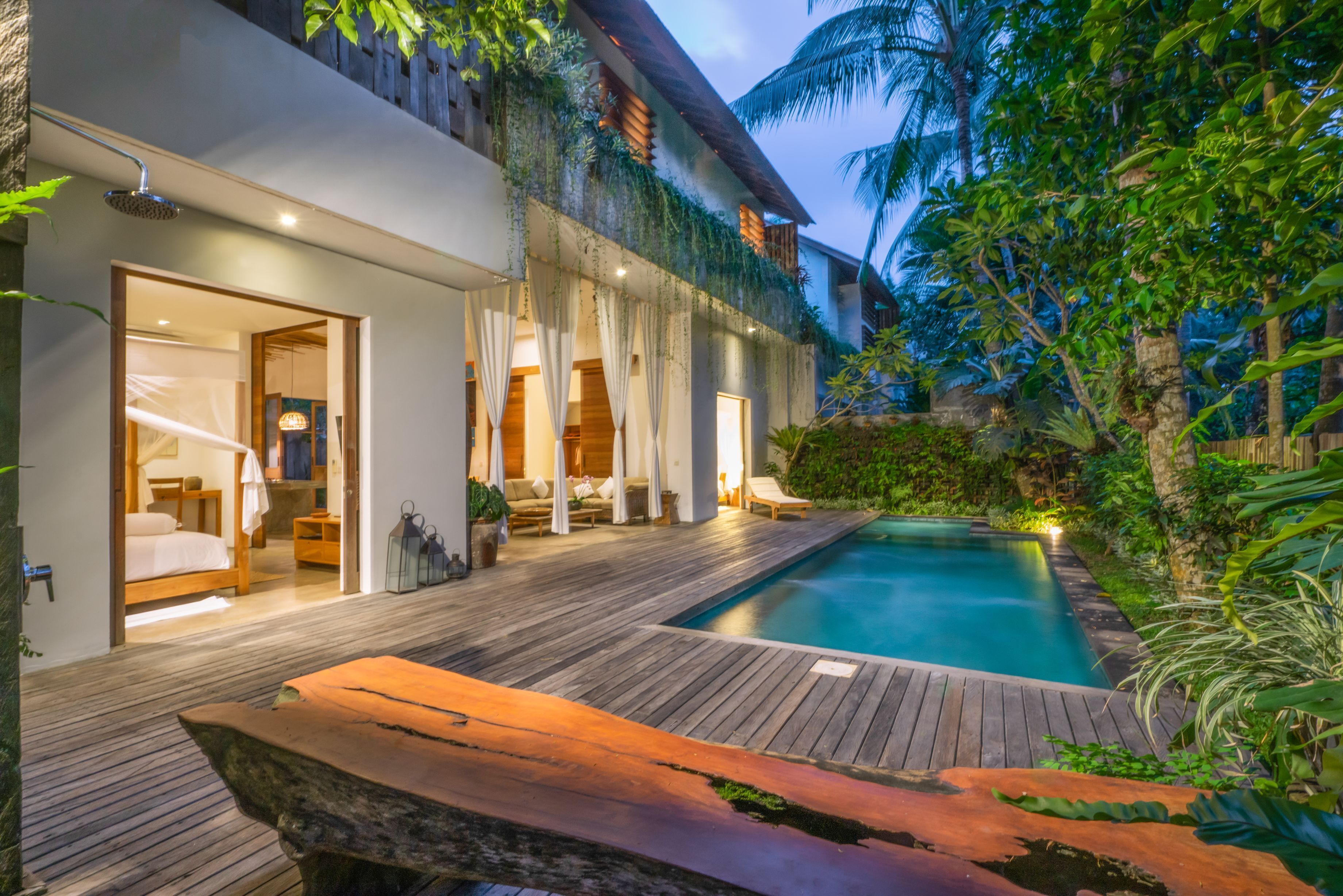 A modern house with a wooden deck, a swimming pool, and a bedroom with a large bed and a bathroom.