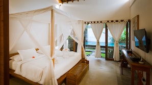 Een slaapkamer met een hemelbed, een houten bureau en een televisie.