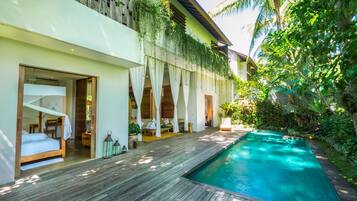 A modern resort with a wooden deck, a swimming pool, and rooms with large windows and curtains.
