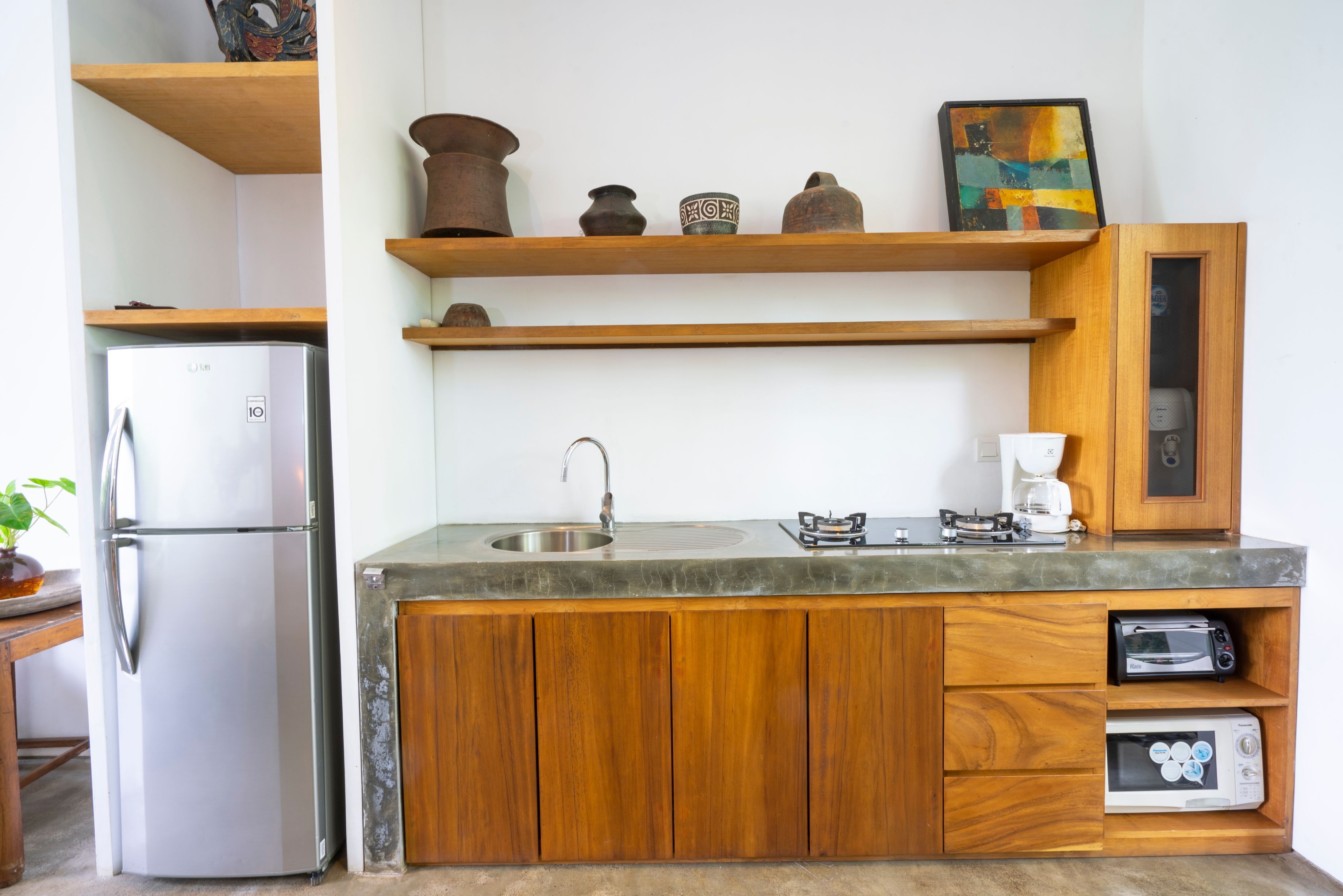 A compact kitchen with a refrigerator, sink, wooden cabinets, and built-in microwave.