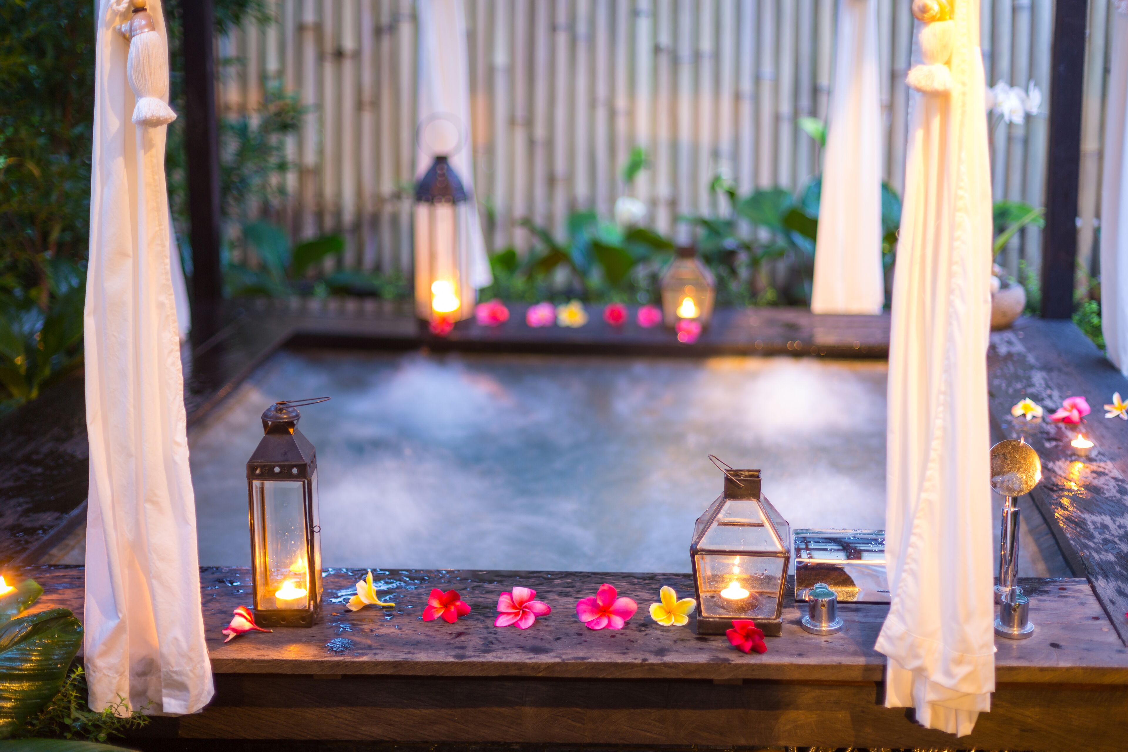 A wooden table with lanterns, candles, and flowers.