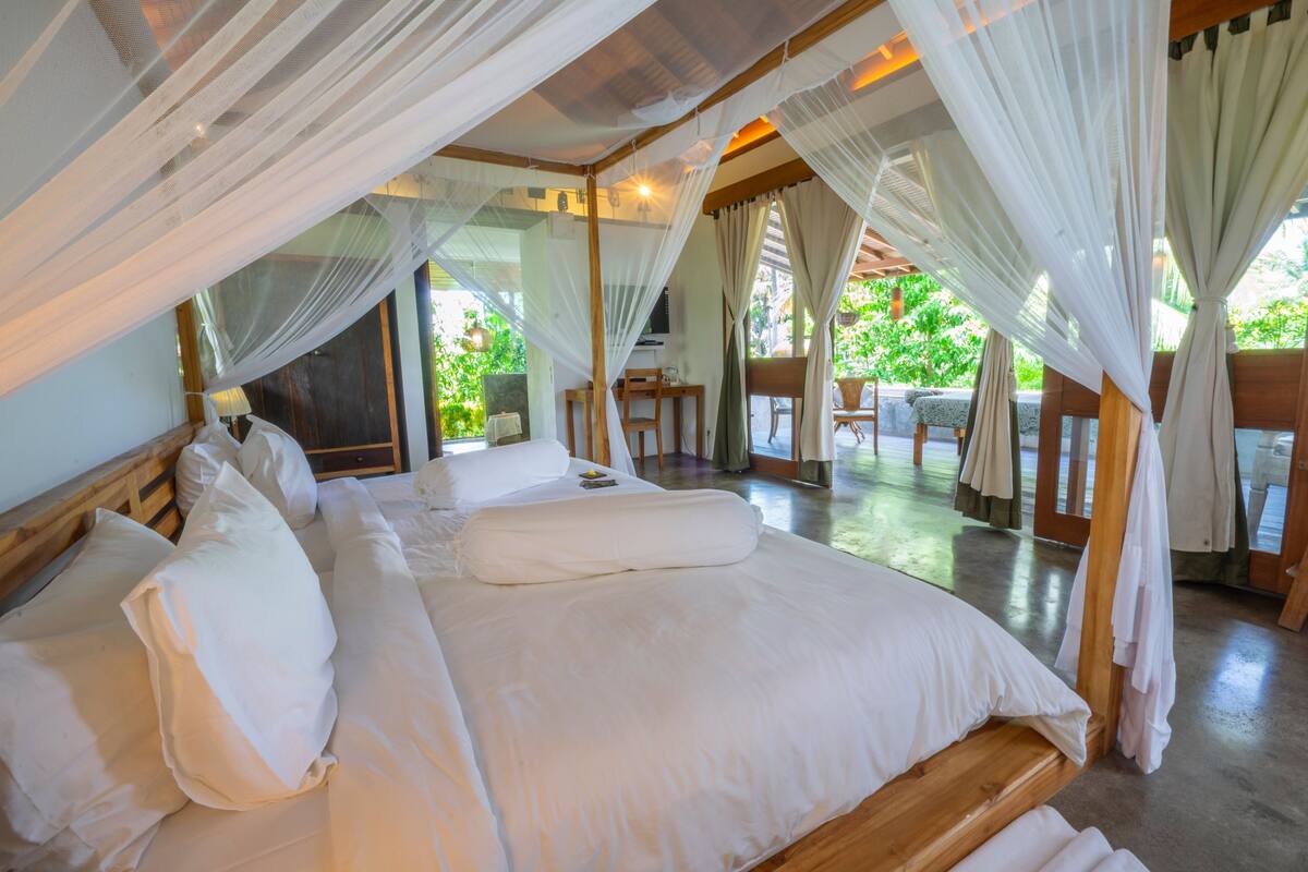 A spacious bedroom with a large bed, white linens, and a canopy bed.