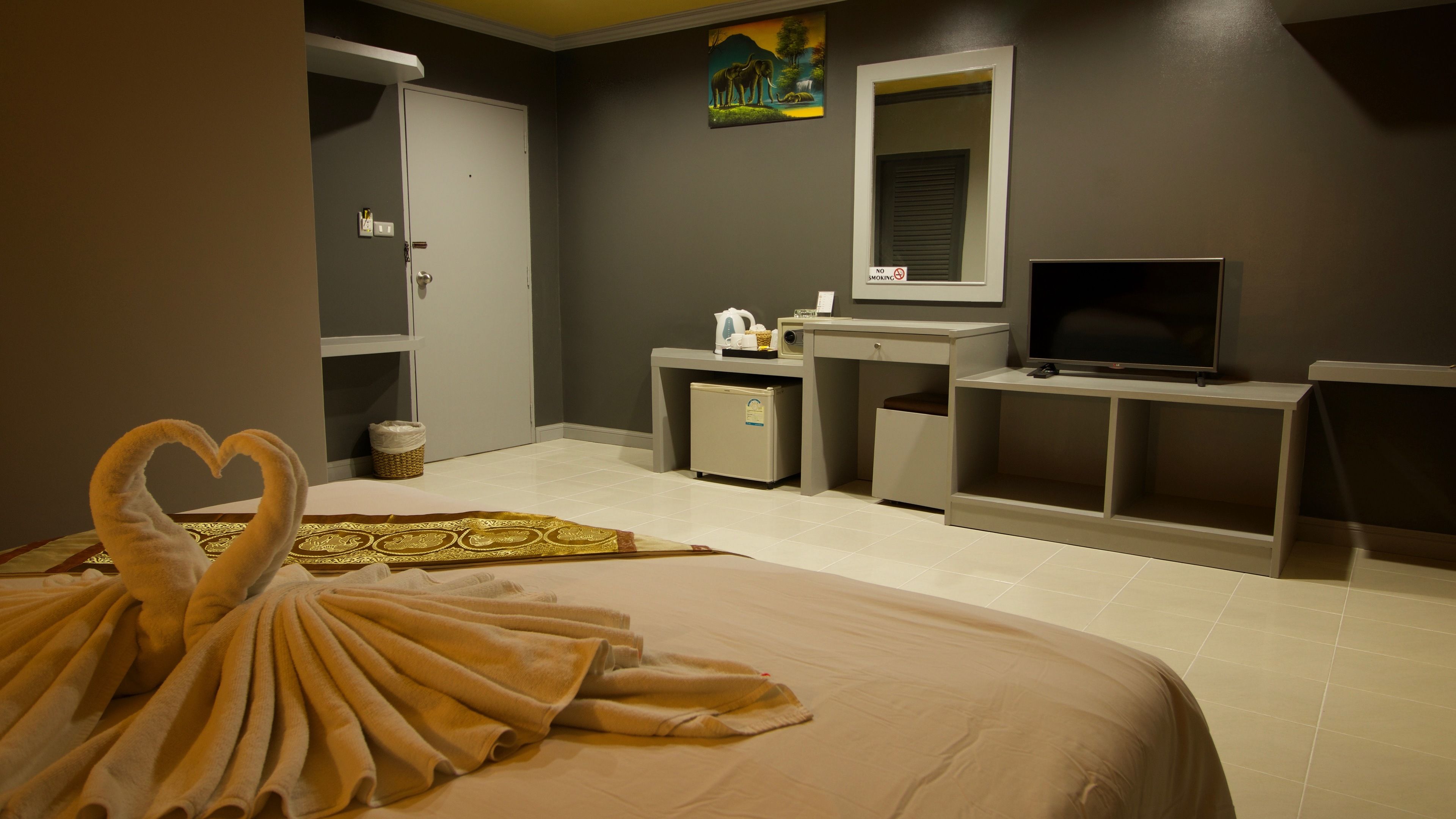 Een hotelkamer met een bed, televisie, bureau, kleine koelkast en een badkamer.