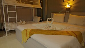 Une chambre d’hôtel avec un lit superposé, une serviette pliée en forme de cœur posée sur le lit et une lampe fixée au mur.