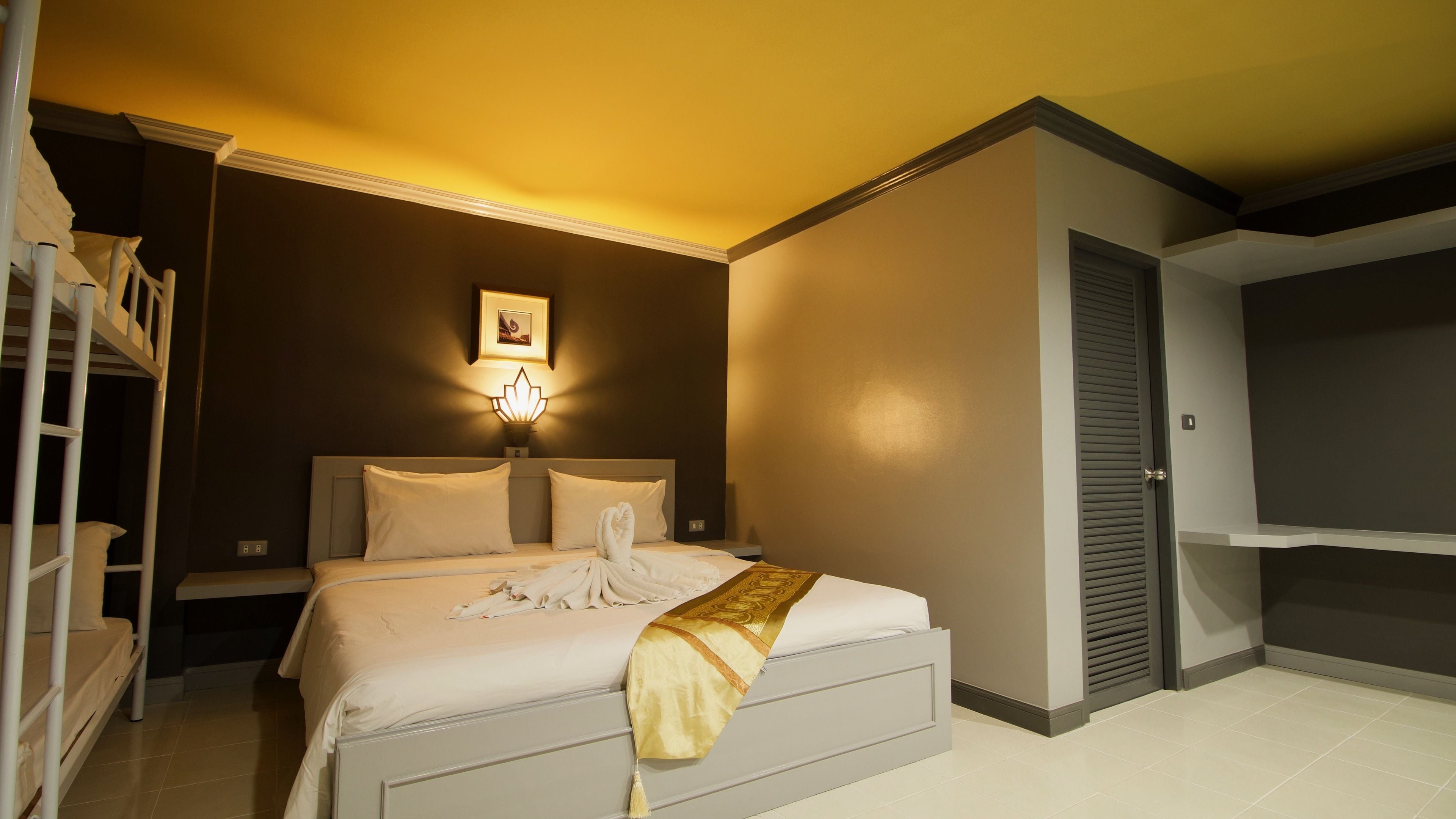 Ein Hotelzimmer mit Bett, Nachttisch, Wandlampe, einem gerahmten Bild und einem Kleiderschrank.