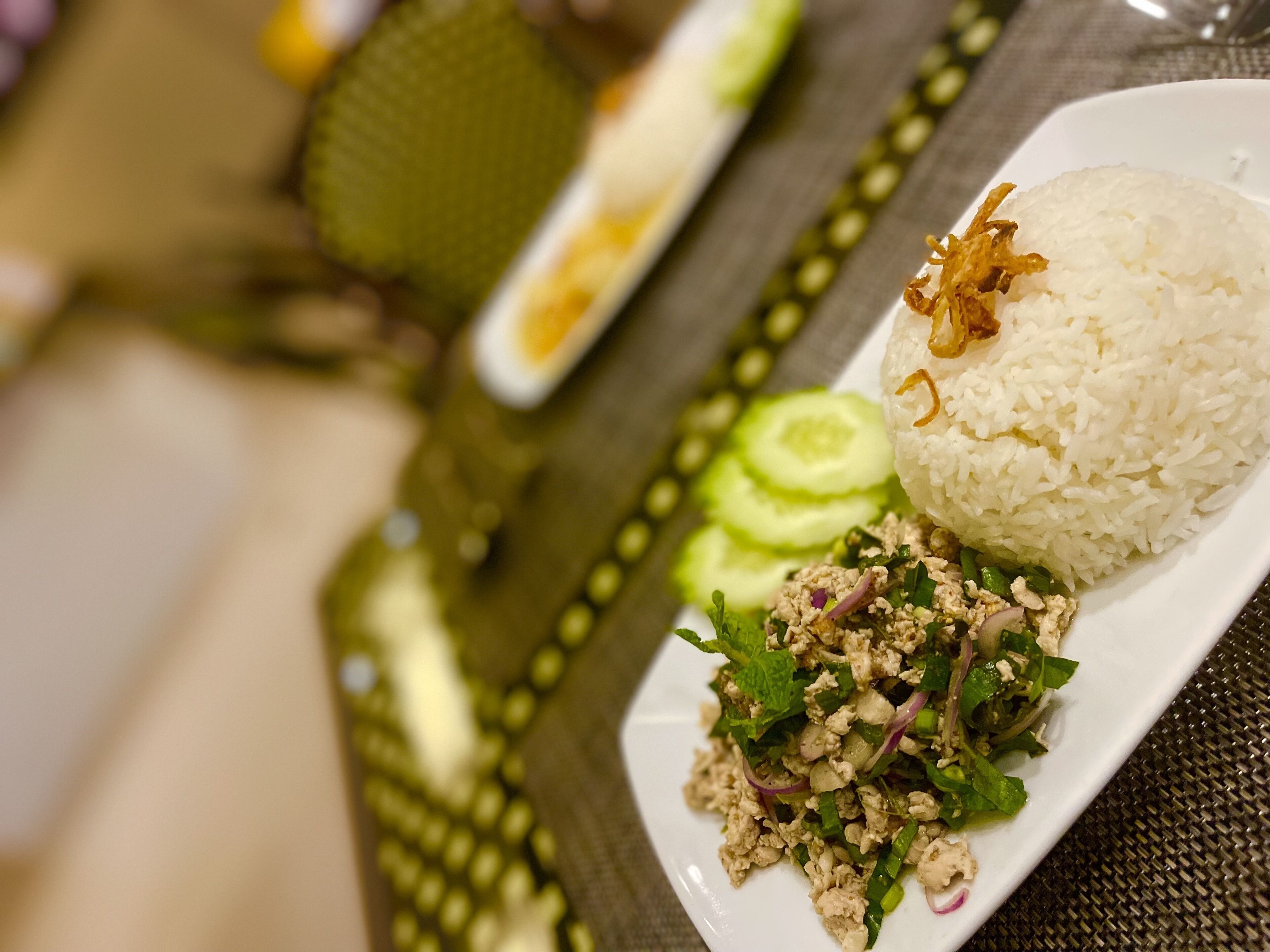 A plate with white rice, a salad, and cucumber slices.
