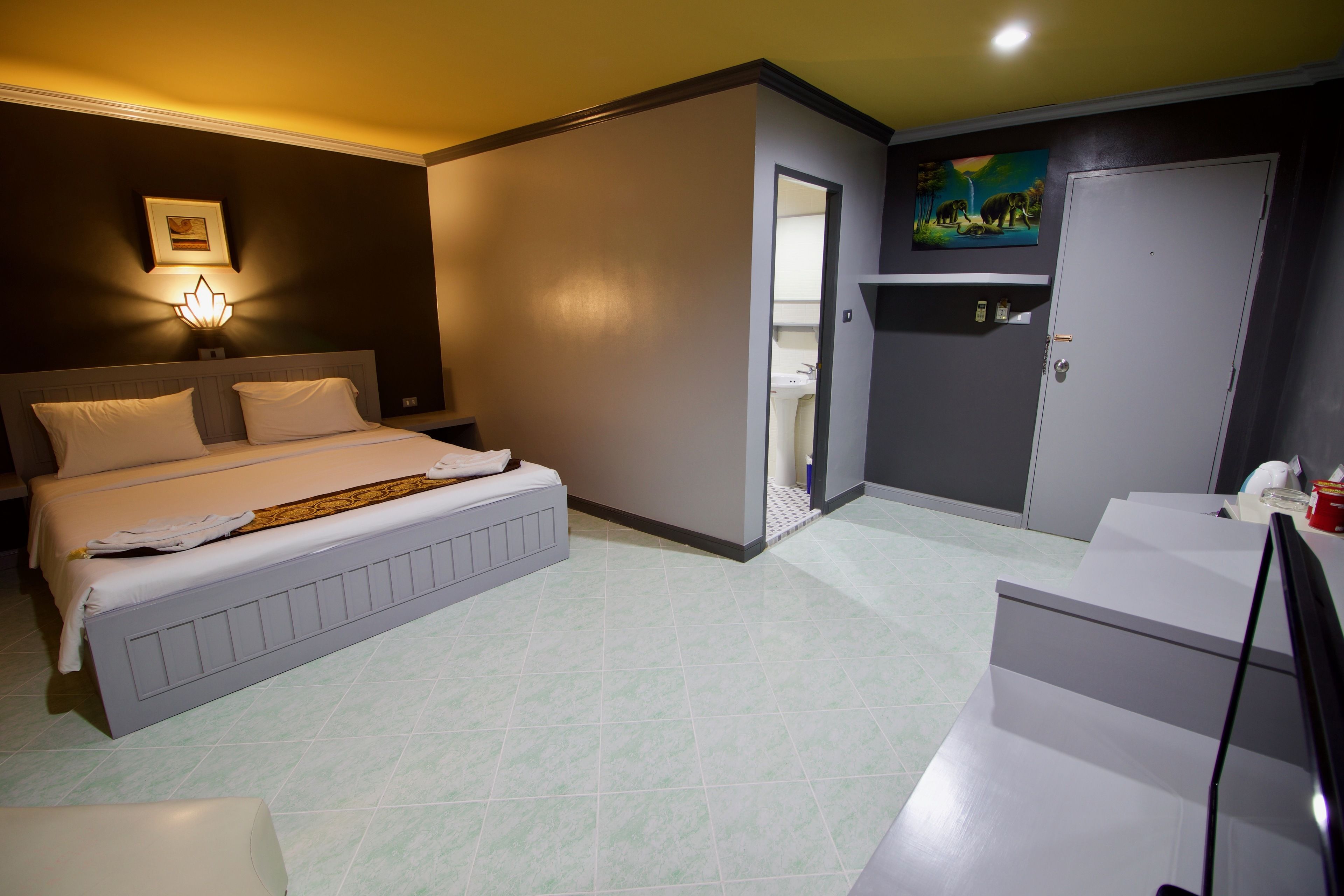 Une chambre d’hôtel avec un grand lit, un bureau, une chaise, une armoire et une salle de bain visible à travers une porte ouverte.