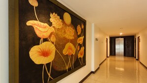 Un couloir orné d’une grande fresque florale sur le mur, doté d’un sol carrelé brillant et terminé par une porte.