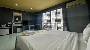 Une chambre d’hôtel équipée d’un lit, d’un bureau, d’une télévision et d’une fenêtre donnant sur un immeuble.